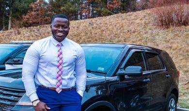 Aboubacar stands next to police cruiser